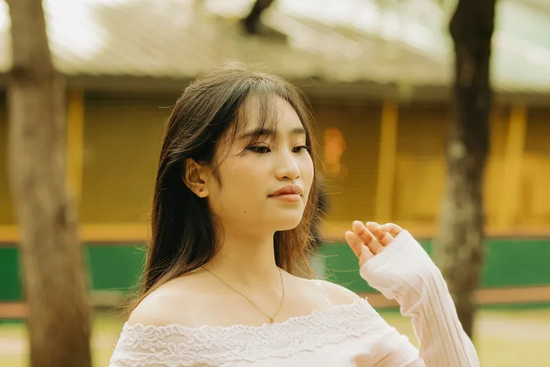 Candid portrait of a young woman with long straight hair in an outdoor park